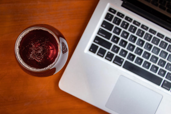 Glass of red wine adjacent to laptop computer